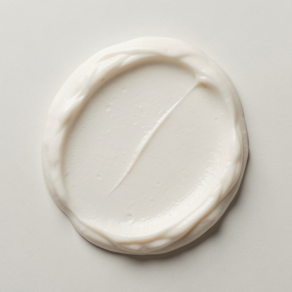 Body cream texture on flat pale surface with overhead editorial shot showing rich emollient consistency